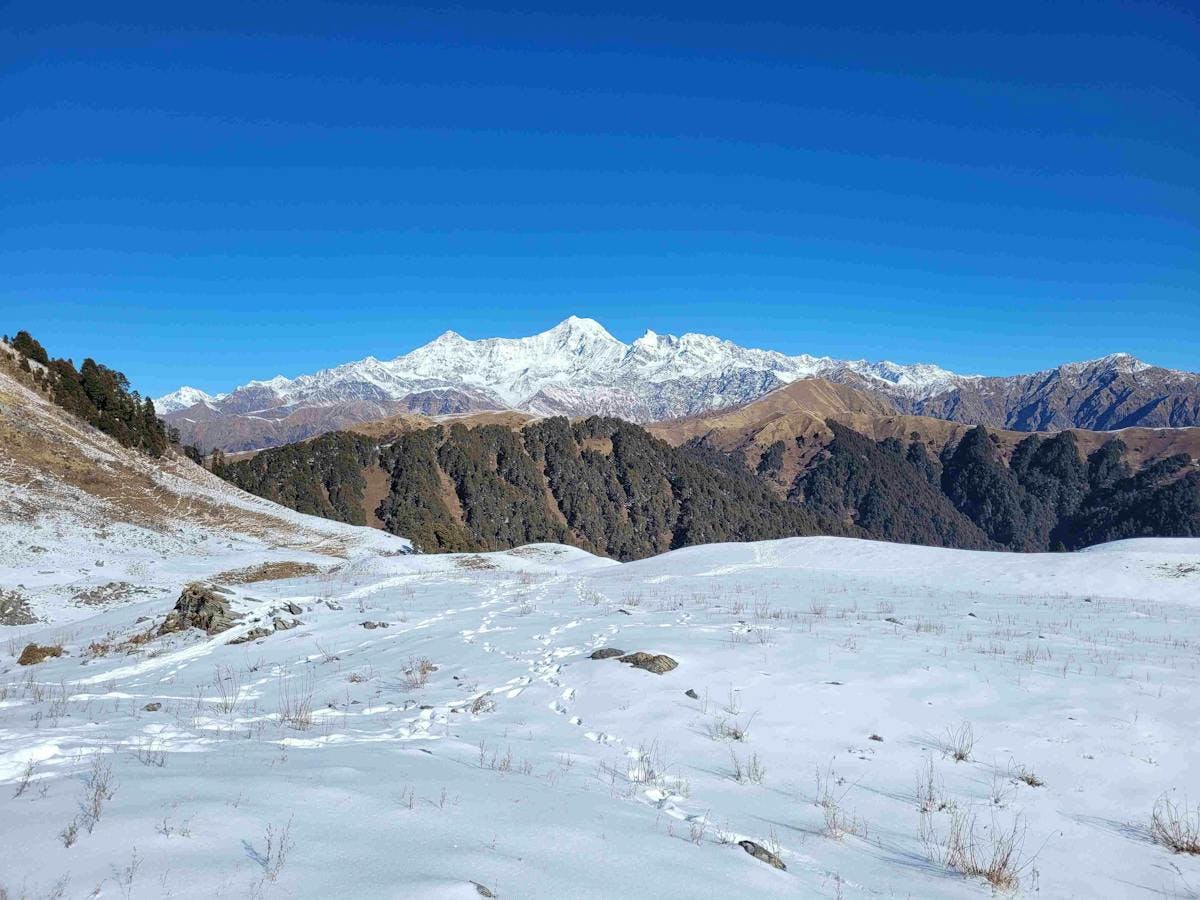 A panoramic view of Dayara Bugyal covered in a blanket of snow, with the Himalayas in the background. Photo by Diptarka Gupta.