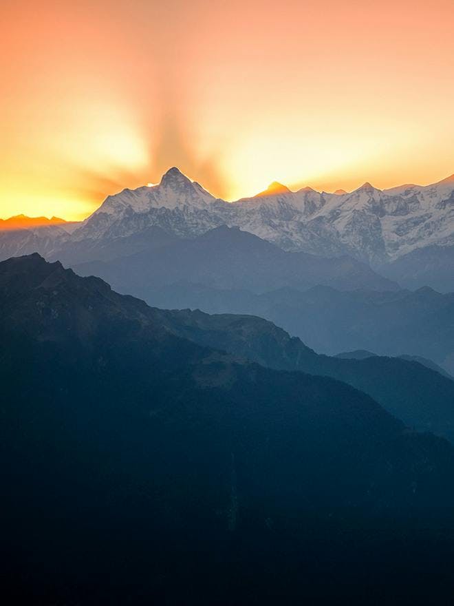 Portrait photo of the sun rising from Mt Nanda Devi the second highest peak in India