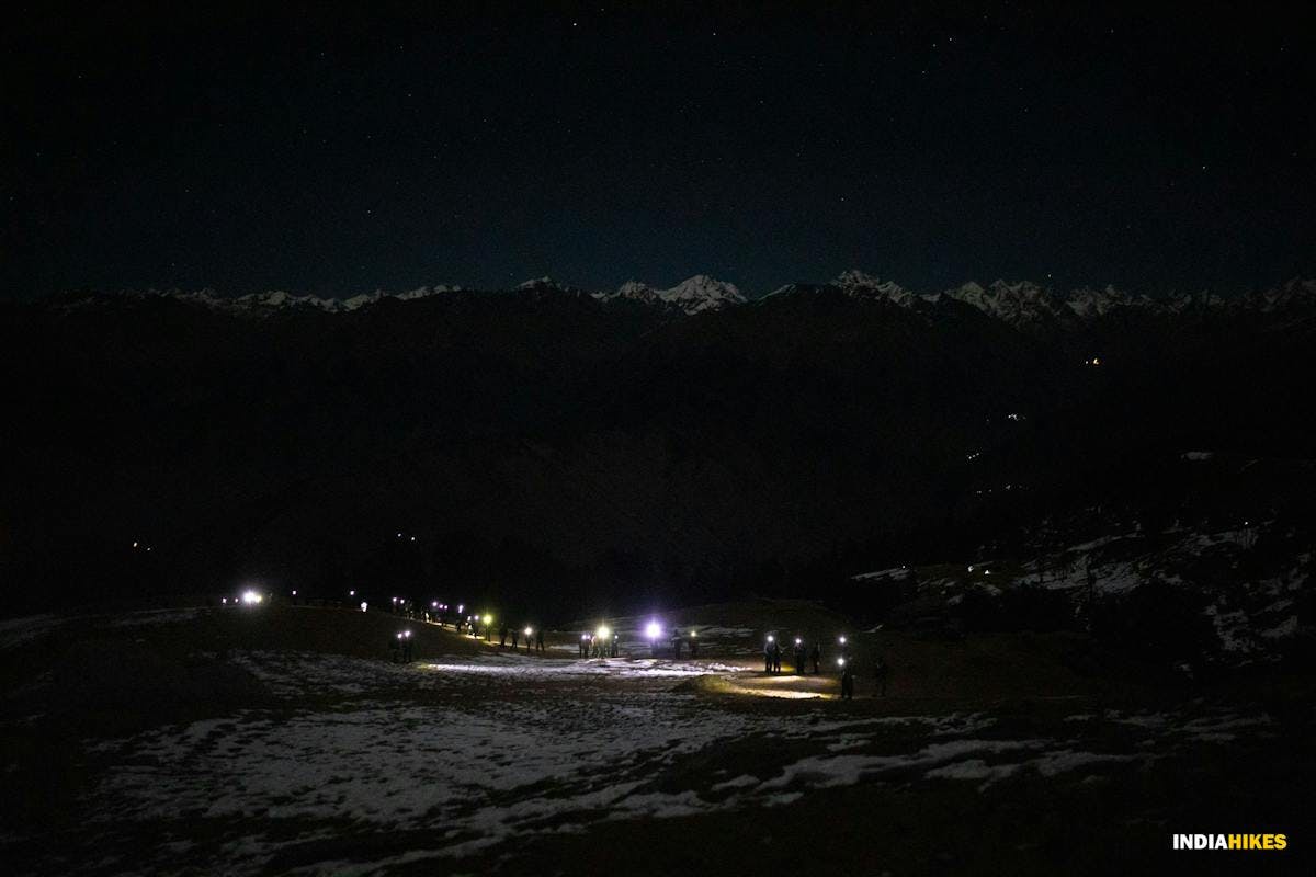 A group of trekkers going for the challenging Kedarkantha summit climb in the dark using torches and lights